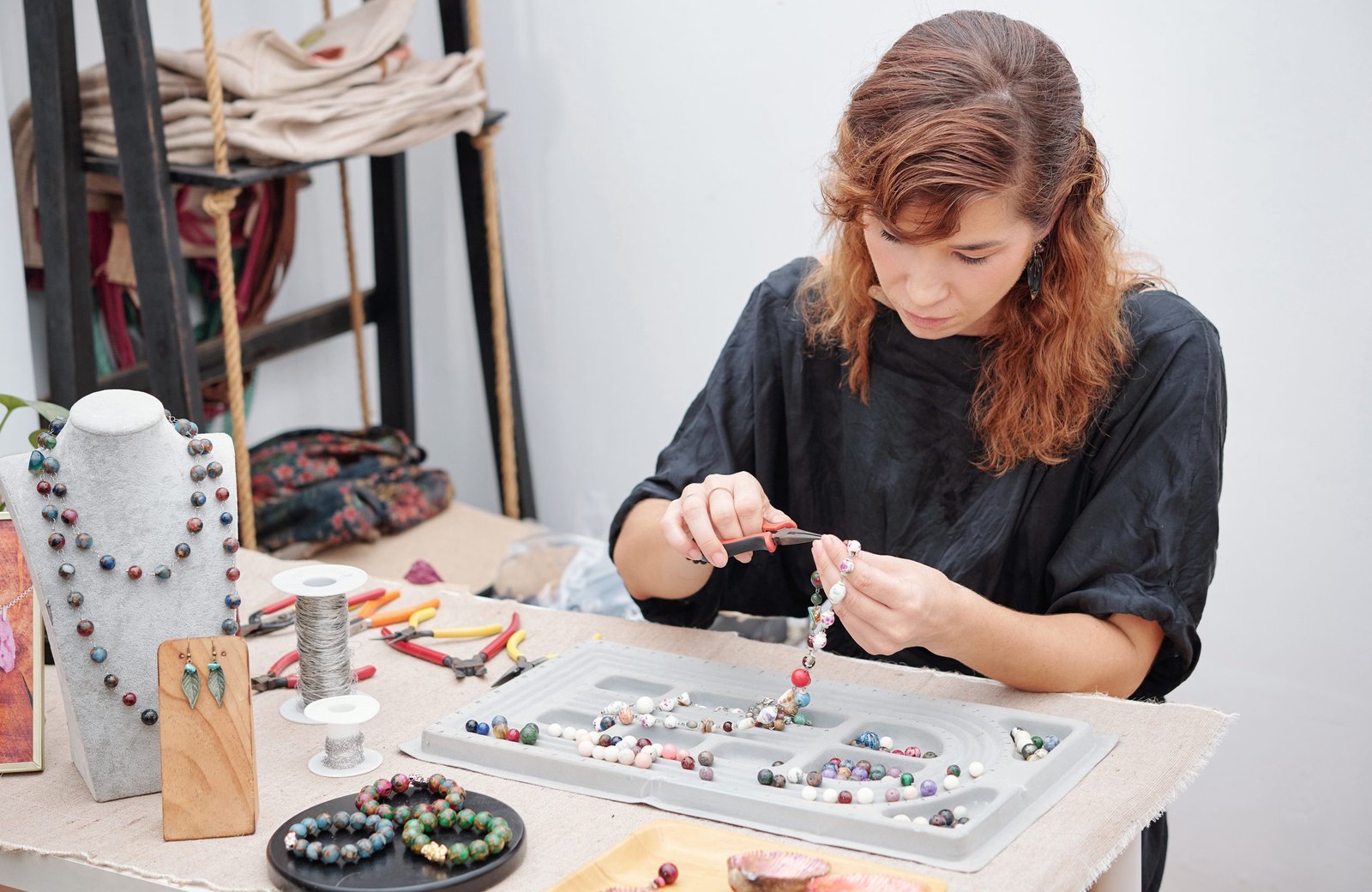 Woman gently cleans golden jewelry with a soft cloth. Hands hold ring with diamonds. Other jewelry pieces are on white table. Home setting. Top view. Closeup shot of, jewelry care.